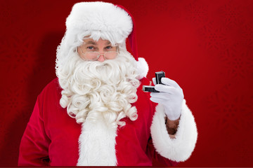 Cheerful santa holding a jewelry box against red snowflake background