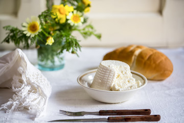 Fresh Italian ricotta with wheat homemade bread on the table, rustic still life composition with spring flowers, Salento, Puglia