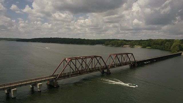 Aerial view of a railroad trestle across a lake with boats going underneath.