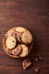 Fototapeta na wymiar Side view of chocolate chip cookies on a wooden plate over rustic background, selective focus