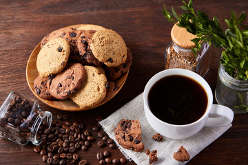 Coffee cup, jar with coffee beans, cookies over rustic background, selective focus, close-up, top view