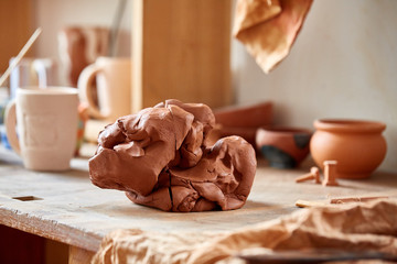 Large piece of red clay closeup on worktop at the potter workshop, close-up, shallow depth of field