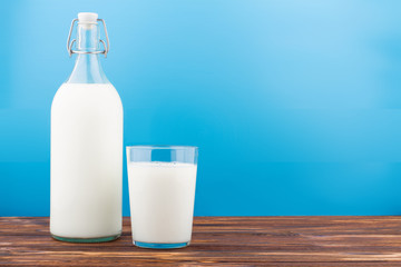 a glass of milk, a bottle of milk on a wooden table 