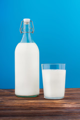 a glass of milk, a bottle of milk on a wooden table 