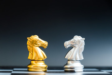 Gold and silver horse chess piece face in chessboard on black background