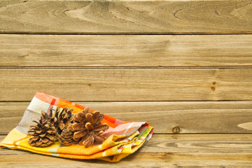 A still life of an autumn colored napkin and pine cones on wood providing copy space.