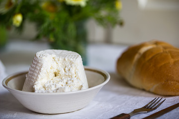 Close up of fresh Italian ricotta with wheat homemade bread on the table, rustic still life composition with spring flowers, Salento, Puglia