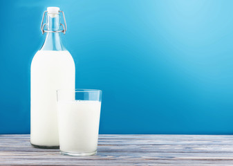 a glass of milk, a bottle of milk on a wooden table 