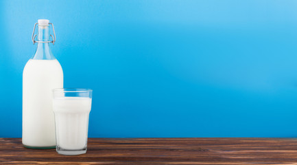 a glass of milk, a bottle of milk on a wooden table 