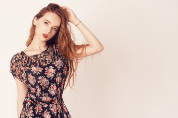 Stylish beauty model girl wearing pretty dress. Fashion beautiful woman with long curly hair wearing sunglasses. Studio shot. Pretty young sexy fashion sensual woman posing on white wall