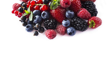 Fruits and berries isolated on white background. Ripe currants, raspberries, blueberries,  strawberries and blackberries with a mint leaf. Sweet and juicy fruits with copy space for text. Top view.