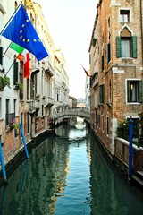 An empty canal in Venice, Italy with a bridge.