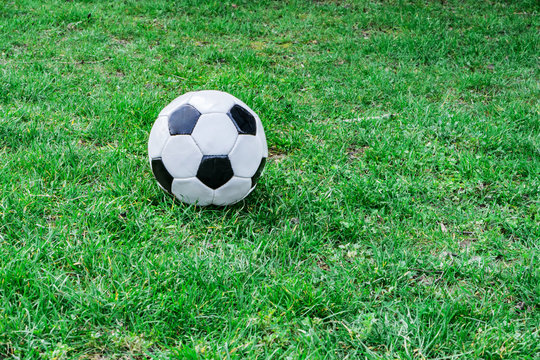 Closeup of white soccer ball on a green grass background. Hobby concept.
