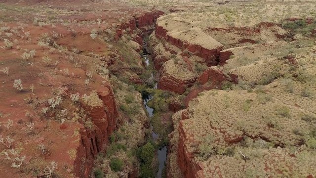 Aerial view flying over canyon gorge viewing river in Karijini in the desert of Western Australia.