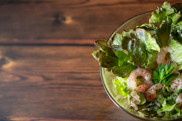 fresh salad with shrimp on wooden background