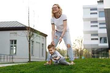 Sun shines behind happy son and mom having fun while they play outside