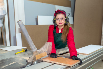 Pretty and young carpentry worker sawing wooden plank