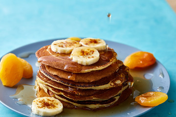 Pile of homemade pancakes with honey and walnuts on rustic wooden background, selective focus