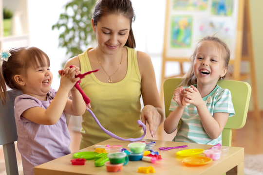 Cheerful children and teacher woman make by hands playing with color dough