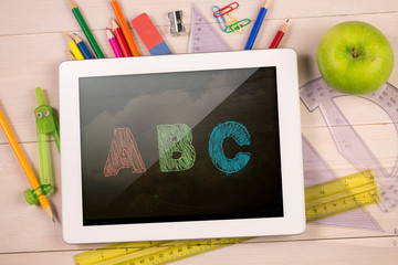 Composite image of digital tablet on students desk showing abc