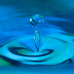 pure water droplet splashing on water surface forming beautiful shapes abstract concept blue hue photo