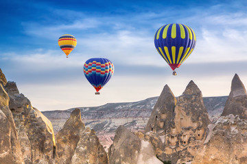 Three bright multi-colored hot air balloons flying in sunsrise sky Cappadocia, Turkey
