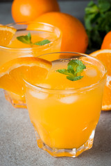 Close-up of a glass of orange juice with oranges fruits on wooden and stone background. Vitamins and minerals. Healthy drink and beverage concept.