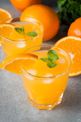 Close-up of a glass of orange juice with oranges fruits on wooden and stone background. Vitamins and minerals. Healthy drink and beverage concept.