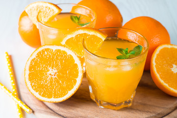 Close-up of a glass of orange juice with oranges fruits on wooden and stone background. Vitamins and minerals. Healthy drink and beverage concept.