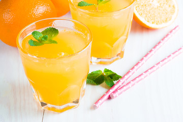 Close-up of a glass of orange juice with oranges fruits on wooden and stone background. Vitamins and minerals. Healthy drink and beverage concept.