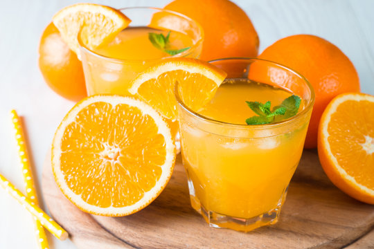 Close-up of a glass of orange juice with oranges fruits on wooden and stone background. Vitamins and minerals. Healthy drink and beverage concept.