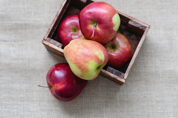 Still life, useful vitamins in fruit, wooden box full of fresh red apples, on sackcloth background