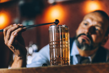 Barman is making cocktail at night club.