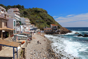 Main view of cala Margarida, a lovely beach surrounded by traditional fishermen's white buildings with colorful doors and windows, Palamos, Costa Brava, Spain.