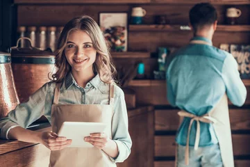 Fotobehang Portrait of beautiful barista in apron with tablet in cafe. © VadimGuzhva