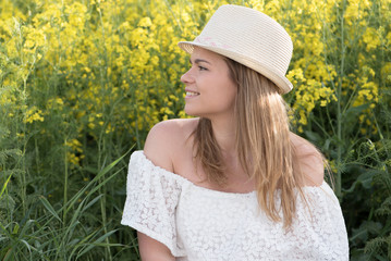 Beautiful young woman wearing hat on the colza field