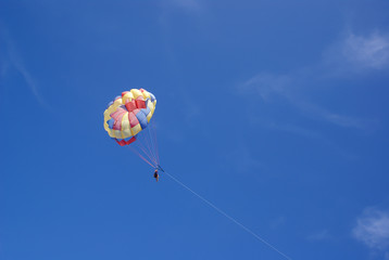 Two people glide with a parachute against the blue sky. Selective focus