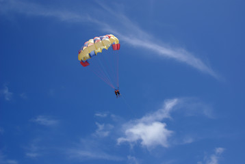 Two people glide with a parachute against the blue sky. Selective focus