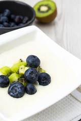 Semolina pudding with kiwi fruit and blueberries, sweet healthy and vegetarian meal concept.