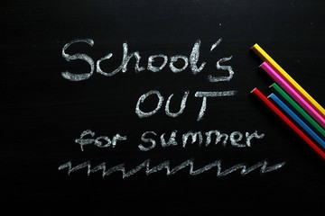 School`s out for summer text and colored pencils on chalkboard