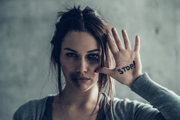 Oppressed woman shows by hand sign stop. Bruises on face.
