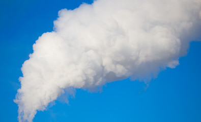 smoke from a pipe in the factory against a blue sky