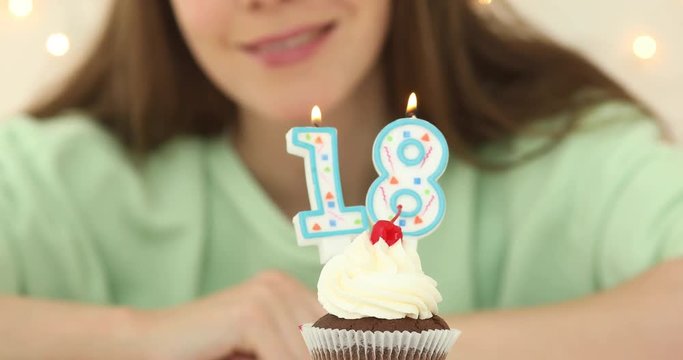 bautiful caucasian girl blowing 18 candles on her cake