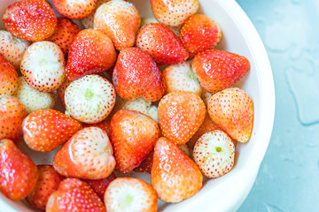 Red strawberries colander are rinsed under water