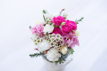 Lovely spring bridal bouquet with pink spray roses, white carnations, violet and white double tulips, waxflower, eustoma and greenery on a white background