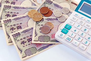 Japanese currency yen bank note with coin and calculator on white background