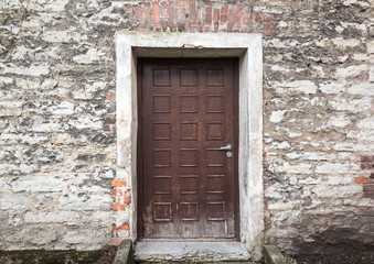 Old brown wooden door in stone wall. Tallinn