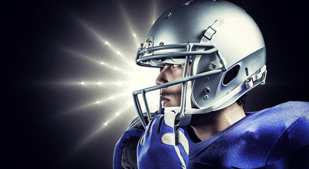 Sportsman wearing helmet looking away against spotlight