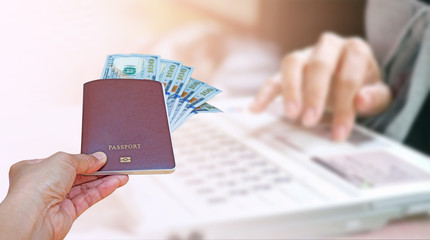hand holding passport and American dollar currency isolated on blurred hand on keyboard, insurance concept