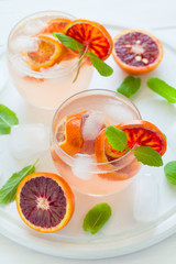 Blood orange cocktail with slices of orange on white wooden background